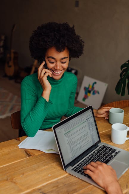pexels-photo-5332221-5332221-1 African American woman with afro hair talking on phone and holding a mug indoors.